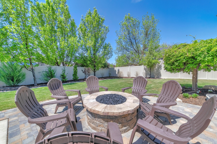 A round stone table with plastic chairs in front of the house